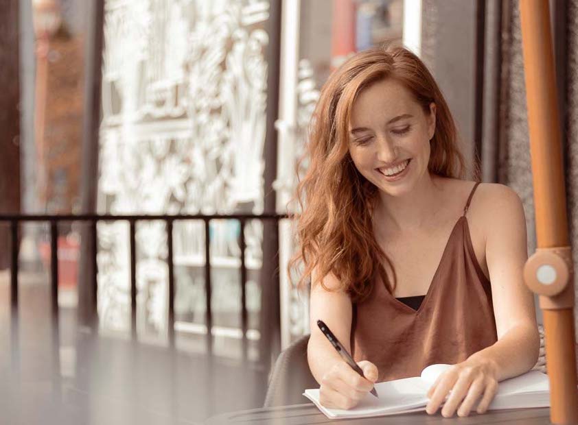 Picture of Emma Wolno Smiling while Writing in her Notebook | 5 Common Blogging Mistakes | Content By Em